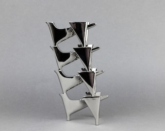 Könnte beinhalten: Eine silberne Metallskulptur aus gestapelten geometrischen Formen. Die Skulptur besteht aus mehreren Teilen, die übereinander gestapelt sind und ein einzigartiges und modernes Design schaffen.