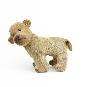 May include: A vintage, worn, tan plush toy dog with red eyes. The dog is standing on a white background.