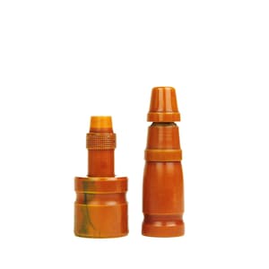 May include: Two brown wooden duck calls with a mottled pattern. The call on the left has a round base and the call on the right has a pointed top.