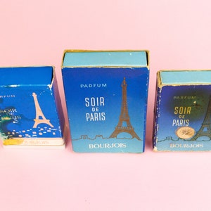 Puede incluir: Tres cajas de perfume azules y doradas con el texto "Parfum Soir de Paris Bourjois" y una imagen de la Torre Eiffel.