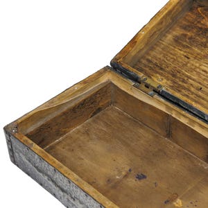 May include: An open, antique wooden box with a hinged lid. The box is made of light brown wood with visible grain and dark accents. The interior is also wooden, with a rectangular shape and a dark stain.