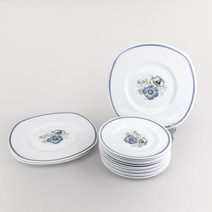 May include: A set of white ceramic plates with a blue floral design. The plates are stacked and ready to be used for a meal.