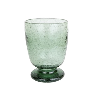 May include: A green-tinted glass goblet with a rounded bowl and a short, circular base. The glass has a speckled texture, and the base is a darker shade of green. The goblet is designed for beverages.
