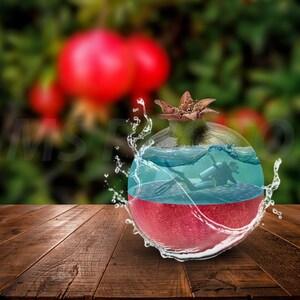 Puede incluir: Imagen digitalmente alterada de una granada con un buceador en su interior. La granada es roja en la parte inferior, con un océano azul y un buceador en el medio, y una parte superior verde. El agua salpica alrededor de la fruta, sobre un fondo borroso de frutos rojos y hojas verdes.