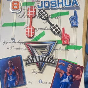 Puede incluir: Un conjunto de adornos para pasteles con los nombres "Thomas" y "Joshua" con el n&uacute;mero "8" en medio. Los adornos est&aacute;n decorados con purpurina y presentan un esquema de colores rojo, blanco y azul. Los adornos tambi&eacute;n est&aacute;n decorados con im&aacute;genes de luchadores y la palabra "Gladiators".