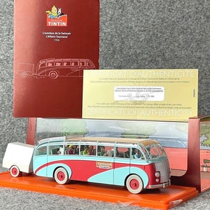 May include: A red, white and blue model bus with a Swissair logo and a trailer. The bus is in a display case with a certificate of authenticity. The certificate states that the model is a limited edition of 12,500 pieces. The model is based on the Tintin comic book series.