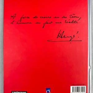 Puede incluir: Portada de libro roja con texto manuscrito en negro. El texto dice: &laquo; A force de croire en des r&ecirc;ves, l'homme en fait une r&eacute;alit&eacute;. &raquo; Debajo, una firma. La editorial es Casterman.
