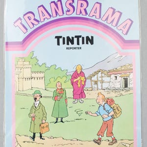 Puede incluir: Paquete de pl&aacute;stico sellado con una portada de c&oacute;mic con el t&iacute;tulo "TRANSRAMA" y "TINTIN REPORTER". La ilustraci&oacute;n representa a Tint&iacute;n y otros personajes en un paisaje monta&ntilde;oso. El logotipo de JESCO est&aacute; en la parte inferior.