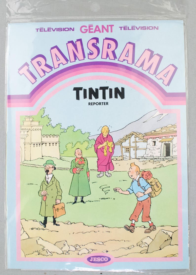 Puede incluir: Paquete de pl&aacute;stico sellado con una portada de c&oacute;mic con el t&iacute;tulo "TRANSRAMA" y "TINTIN REPORTER". La ilustraci&oacute;n representa a Tint&iacute;n y otros personajes en un paisaje monta&ntilde;oso. El logotipo de JESCO est&aacute; en la parte inferior.