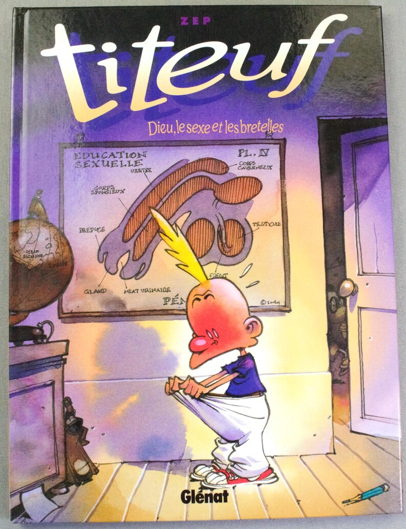 Puede incluir: Un libro de tapa dura titulado Titeuf: Dieu, le sexe et les bretelles de Zep. La portada muestra un personaje de dibujos animados con un mech&oacute;n de pelo amarillo tirando de sus pantalones blancos, frente a un cartel con el texto Education Sexuelle y diagramas anat&oacute;micos.