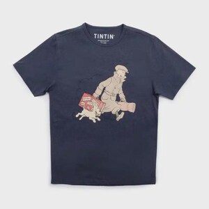 May include: Navy blue t-shirt featuring a graphic of Tintin, his dog Snowy, and luggage. The word "TINTIN" is printed at the top of the shirt. The illustration depicts Tintin running with Snowy and luggage.