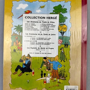 May include: A vintage hardcover book featuring the "Collection Herg&eacute;" series, with illustrations and text in French. The cover displays various Tintin adventures, including "Tintin in America" and "The Secret of the Unicorn." The book is wrapped in clear plastic.
