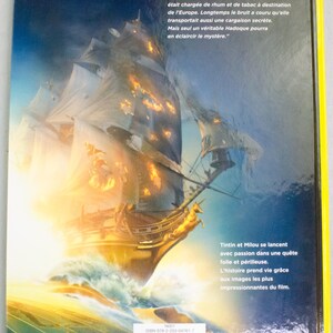 May include: Book cover depicting a sailing ship on a stormy sea, with a yellow border. The ship is golden with fiery highlights. French text describes Tintin and Milou's adventure, with a barcode and ISBN.
