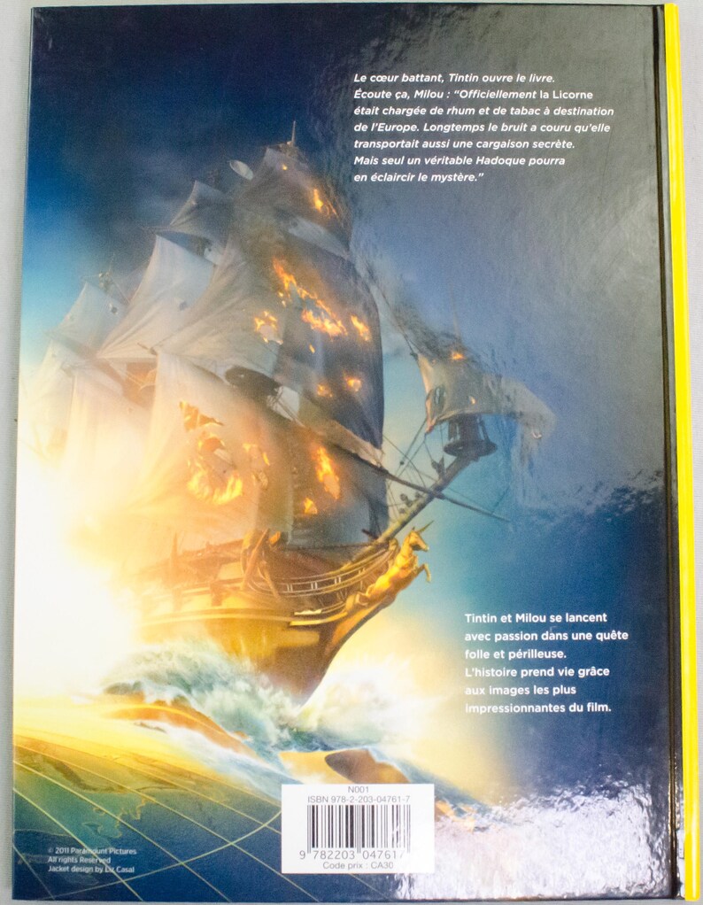May include: Book cover depicting a sailing ship on a stormy sea, with a yellow border. The ship is golden with fiery highlights. French text describes Tintin and Milou's adventure, with a barcode and ISBN.