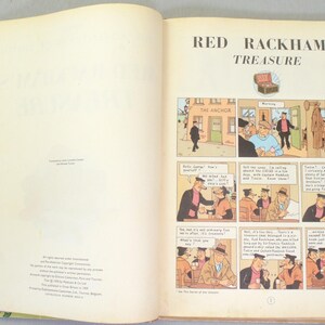 May include: Open book with the title "Red Rackham's Treasure" and comic strip illustrations. The comic panels depict scenes with characters in various settings, including a bar called "The Anchor". The pages are off-white with text and illustrations.