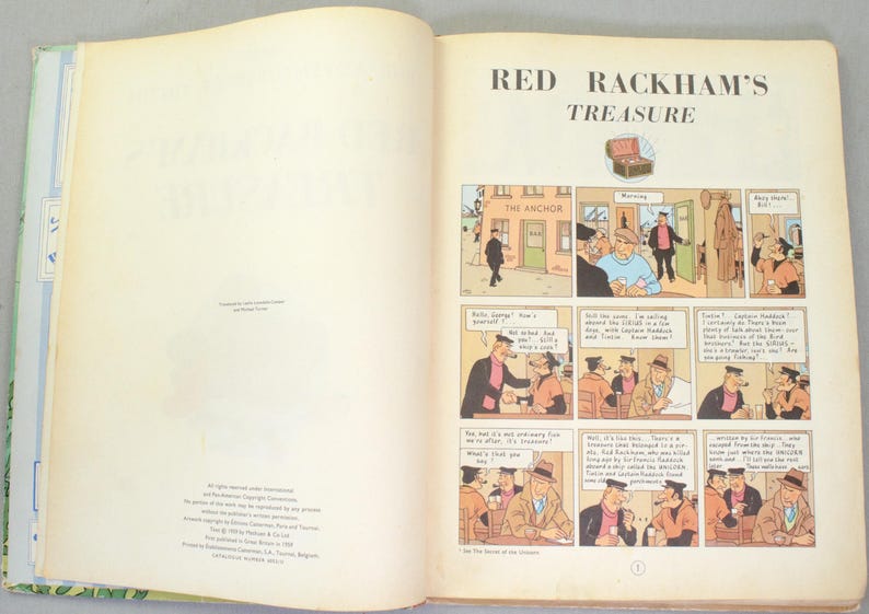 May include: Open book with the title "Red Rackham's Treasure" and comic strip illustrations. The comic panels depict scenes with characters in various settings, including a bar called "The Anchor". The pages are off-white with text and illustrations.