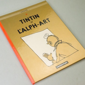 Może przedstawiać: Twarda oprawa książki "Tintin et l'Alph-Art" autorstwa Herg&eacute;. Złota okładka z czarnym tytułem i szkicem Tintina. Grzbiet w jaskrawym pomarańczu. Wydane przez Casterman.