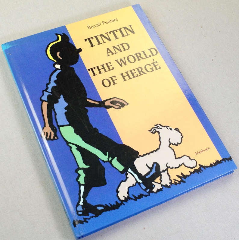 Puede incluir: Un libro titulado "Tint&iacute;n y el mundo de Herg&eacute;" con una cubierta azul, amarilla y blanca. La portada presenta una ilustraci&oacute;n de dibujos animados de Tint&iacute;n y su perro Mil&uacute;. El libro es de Beno&icirc;t Peeters.