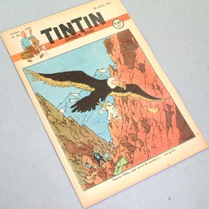 May include: A vintage Tintin comic magazine cover dated August 28, 1947, featuring a large black eagle carrying a white dog in its talons over a rocky mountain landscape. The title Tintin is printed in bold black letters at the top with a price of 4.00 FRS.