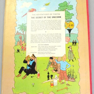 May include: The back cover of a vintage comic book titled "The Adventures of Tintin: The Secret of the Unicorn." The cover features colorful illustrations of characters, a ship, and text. The book is part of a series, with other titles listed.