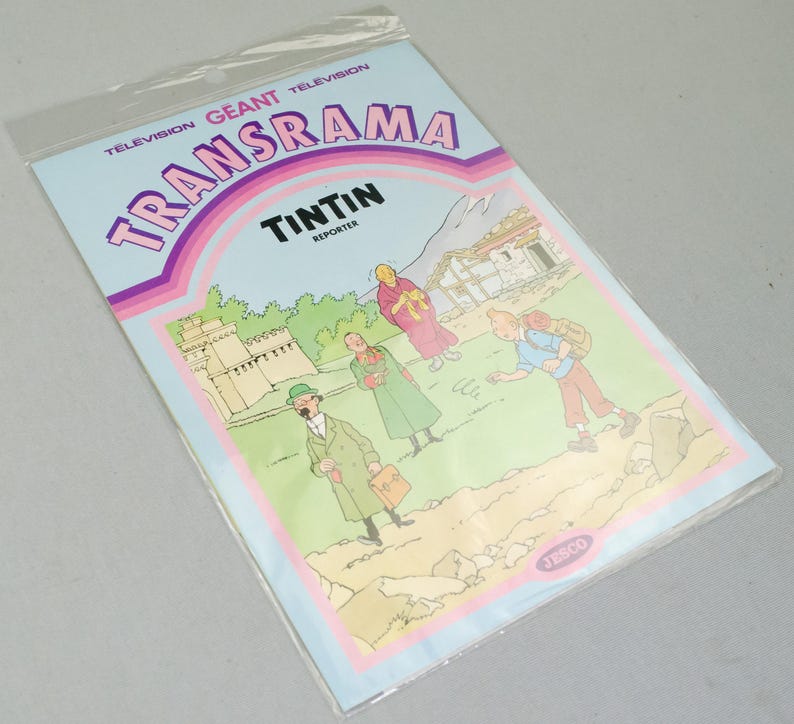 Puede incluir: Un c&oacute;mic vintage "Transrama" con Tint&iacute;n, el reportero. La portada tiene un fondo azul claro con el t&iacute;tulo en rosa y morado. La ilustraci&oacute;n muestra personajes en un paisaje monta&ntilde;oso.