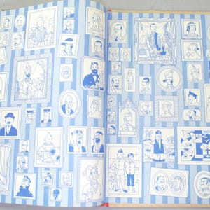 Op de afbeelding: Open boek met blauw-wit gestreepte pagina's, met talrijke ingelijste illustraties van mensen. De illustraties zijn in blauwe inkt, wat een vintage uitstraling geeft. De boekband is zwart.