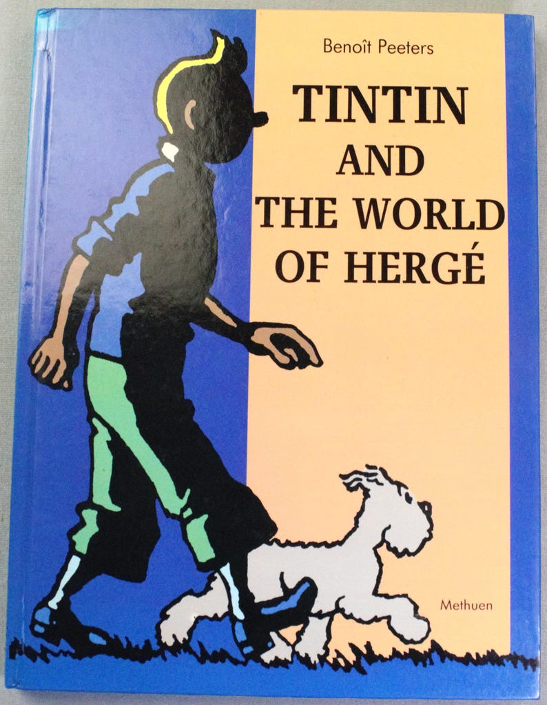 Puede incluir: Portada del libro con Tint&iacute;n y Mil&uacute; caminando. El t&iacute;tulo es "Tint&iacute;n y el Mundo de Herg&eacute;" de Beno&icirc;t Peeters. El fondo est&aacute; dividido entre azul y beige. Publicado por Methuen.