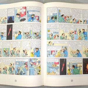 K&ouml;nnte beinhalten: Offenes Comicbuch mit illustrierten Panels. Die Szenen zeigen Charaktere in verschiedenen Umgebungen, darunter ein Raketenstart. Die Illustrationen enthalten Sprechblasen und sind im Retro-Stil gehalten, mit Fokus auf Handlung und Dialog.