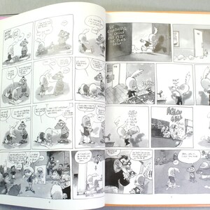 Puede incluir: Un libro abierto que presenta tiras c&oacute;micas en blanco y negro con ilustraciones de personajes de dibujos animados. Las p&aacute;ginas contienen m&uacute;ltiples marcos con globos de texto y texto en franc&eacute;s, mostrando varias escenas e interacciones.