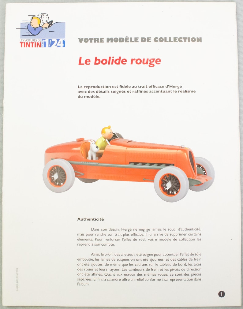Pu&ograve; includere: Un'auto giocattolo arancione con ruote bianche, con un conducente e una statuina di cane. L'auto &egrave; un modello di "Le bolide rouge" della serie Tintin. L'immagine include testo in francese.