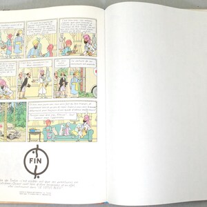 Pode incluir: Livro aberto com pain&eacute;is de banda desenhada com personagens de desenhos animados com turbantes. Os pain&eacute;is mostram diferentes cenas com bal&otilde;es de fala. A palavra "FIN" est&aacute; num c&iacute;rculo na parte inferior, com texto por baixo. A p&aacute;gina direita est&aacute; em branco.