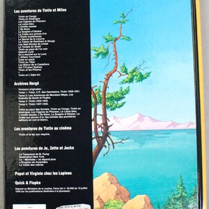 May include: Back cover of a book featuring a scenic illustration of a lake, mountains, and trees. The book's title is "albums d'herg&eacute;" with a list of Tintin adventures in French. The book has a black spine and a yellow border.