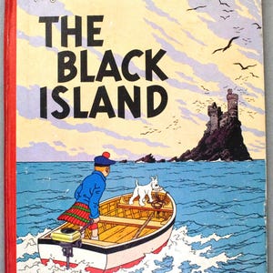K&ouml;nnte beinhalten: Vintage Buchcover von "Die Schwarze Insel" aus der Reihe "Tim und Struppi". Das Cover zeigt Tim und seinen Hund in einem Boot, das sich einer dunklen Insel mit Burg n&auml;hert. Das Buch hat einen roten Buchr&uuml;cken und den Verlag.