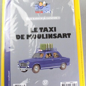 May include: A packaged collectible featuring a blue car with luggage on top, labeled "LE TAXI DE MOULINSART." The cover includes the text "LES BIJOUX DE LA CASTAFIORE" and "TINTIN 1/24." The packaging is yellow with French text.