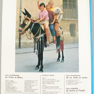 Puede incluir: Portada de libro con una fotograf&iacute;a de cuatro ni&ntilde;os montados en un burro decorado, sonriendo y saludando. El t&iacute;tulo y el autor del libro est&aacute;n en franc&eacute;s, con un fondo azul y blanco. El libro forma parte de la serie "Collection Herg&eacute;".