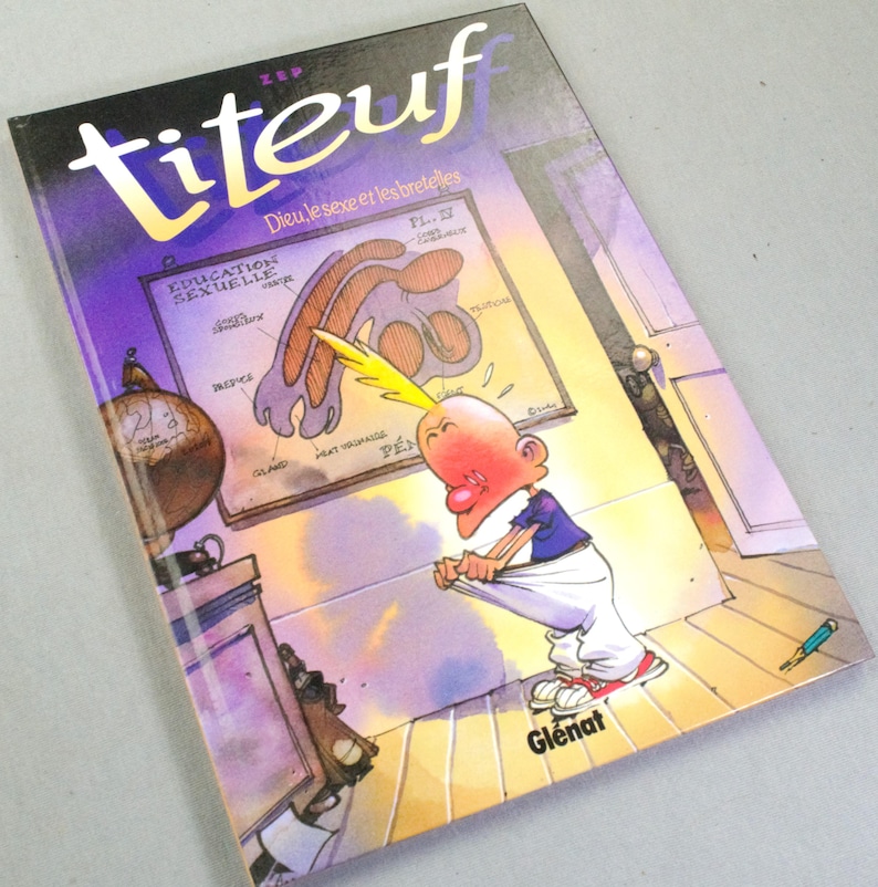 Puede incluir: Un c&oacute;mic de Titeuf titulado Dieu, le sexe et les bretelles de Zep. La portada muestra a un personaje de dibujos animados con un mech&oacute;n de pelo amarillo mirando dentro de sus pantalones blancos, ante un diagrama anat&oacute;mico Education Sexuelle.