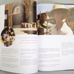 May include: A book spread with photographs and text. One image shows a person in a safari hat. Another image shows an archway and sacks. French text reads "TINTIN EST REVOLTE PAR L'IMPUDEUR DE BEN SALAAD: IL ACCAPARE POUR LUI SEUL L'EAU DE LA VILLE."