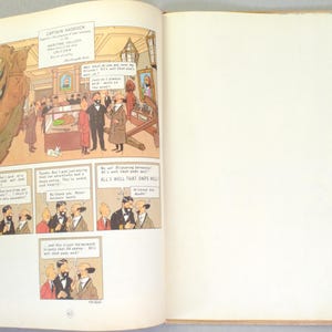 May include: Open book with a comic strip illustration. The comic strip features a museum scene with characters in suits and coats, and speech bubbles. Text at the top reads "CAPTAIN HADDOCK". The right page is blank.