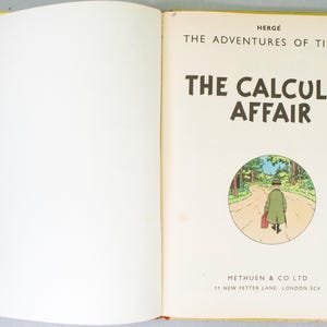 May include: An open book featuring the title page of "The Calculus Affair" from the Tintin series. The page has the title in large, bold letters, a circular illustration of a man walking on a road, and the publisher's information.