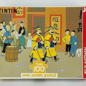 Peut inclure: Un puzzle de 100 pi&egrave;ces repr&eacute;sentant des personnages de la s&eacute;rie de bandes dessin&eacute;es Tintin. Le puzzle repr&eacute;sente une sc&egrave;ne du livre "Le Lotus Bleu" avec Tintin et son chien Milou dans un march&eacute; de rue chinois. La bo&icirc;te de puzzle comprend un poster.