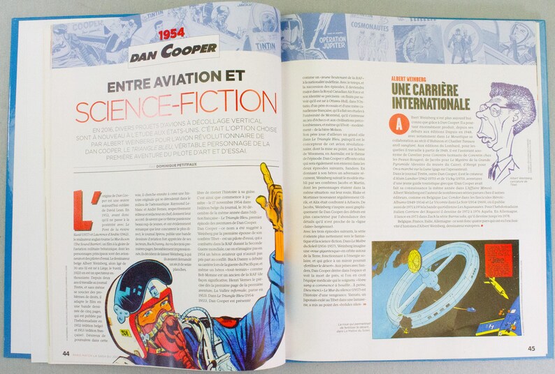 May include: An open book with a blue cover, featuring articles and illustrations. The left page has the title "ENTRE AVIATION ET SCIENCE-FICTION" and a comic illustration. The right page has the title "UNE CARRI&Egrave;RE INTERNATIONALE" and a cartoon drawing.