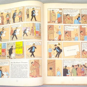 May include: Open book with comic strip illustrations. The panels depict scenes with characters in various settings, including a newspaper stand with the text "DAILY REPORTER". The comic strip is titled "Red Rackham's Treasure".