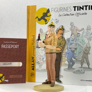 May include: A brown and tan figurine of Captain Haddock from the Tintin comic series. He is holding a bottle of alcohol and a glass. The figurine is standing on a base with the text "Allan provoque Haddock" and the number "21". The background is a book cover with the text "Figurines Tintin La Collection Officielle" and a picture of Tintin running.