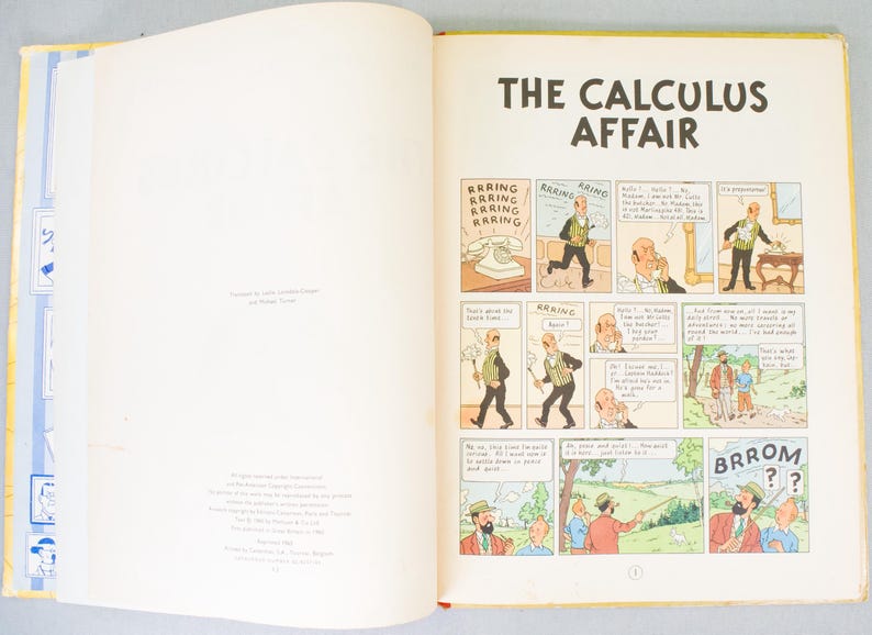 May include: Open book with a yellow cover, displaying a comic strip titled "The Calculus Affair." The comic features panels with illustrations and speech bubbles. The pages are cream-colored.
