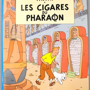 Pode incluir: Capa de "Os Charutos do Fara&oacute;" de Herg&eacute;. Tintin, com camisa amarela e cal&ccedil;as castanhas, e o seu c&atilde;o Milu s&atilde;o retratados. O t&iacute;tulo est&aacute; em letras pretas grandes. M&uacute;mias em sarc&oacute;fagos vermelhos.