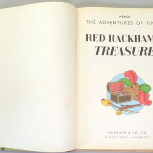 May include: An open book with the title "Red Rackham's Treasure" by Herg&eacute;. The cover features an illustration of a treasure chest, feathers, and other items. The book is from Methuen & Co Ltd.