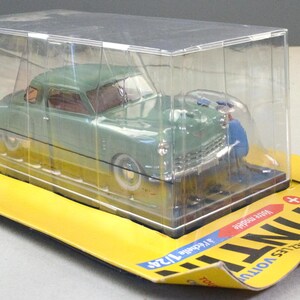 Pu&ograve; includere: Un'auto modello pressofusa verde in una vetrina trasparente, su una base di cartone gialla. L'auto misura circa 18 cm di lunghezza. La confezione presenta testo e illustrazioni in francese.