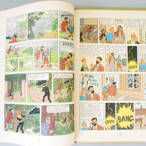 May include: Open book with colorful comic strip panels. The illustrations feature characters in various scenes with speech bubbles. Text includes "WOODOV", "BARROW", "GLING BLING CLING", and sound effects like "CRACK" and "BANG".