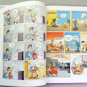 K&ouml;nnte beinhalten: Ein aufgeschlagenes Comicbuch mit farbigen Illustrationen und franz&ouml;sischem Text. Die linke Seite zeigt eine mehrteilige Sequenz mit Charakteren in einem Wohnzimmer, w&auml;hrend die rechte Seite verschiedene Szenen in Innen- und Au&szlig;enbereichen darstellt.