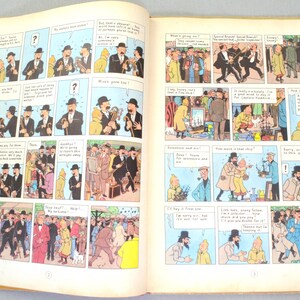May include: Open book with comic strip illustrations. The pages display panels with characters in suits and hats, engaging in conversations. The comic strip is in color, with speech bubbles and sequential storytelling.